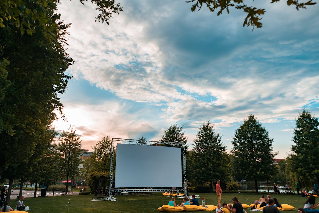 Experience the charm of an open-air cinema surrounded by lush greenery and a beautiful sunset.