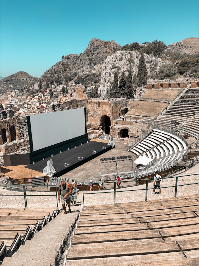 Ancient Greek theater in Sicily with a modern screen setup, blending history and technology.